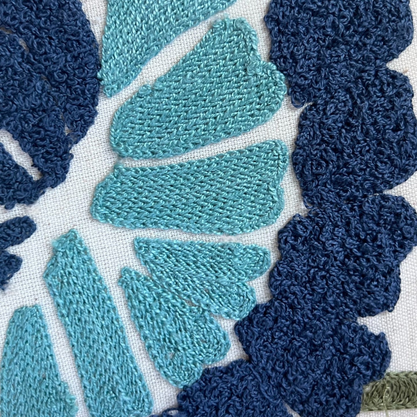 Close-up of textured fabric with blue and green leaf patterns on a white background