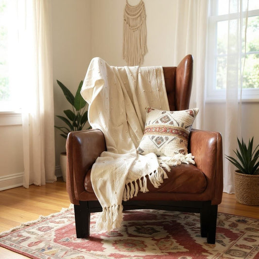 Beige armchair with a white blanket draped over it in a cozy room.